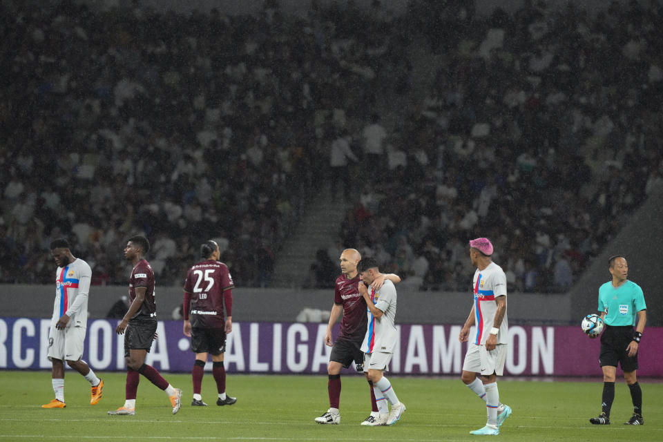 Vissel Kobe's Andres Iniesta, center, walk with a Barcelona's player during a friendly soccer match between his Japanese club Vissel Kobe and his old club Barcelona at the National Stadium in Tokyo, Tuesday, June 6, 2023. (AP Photo/Eugene Hoshiko)