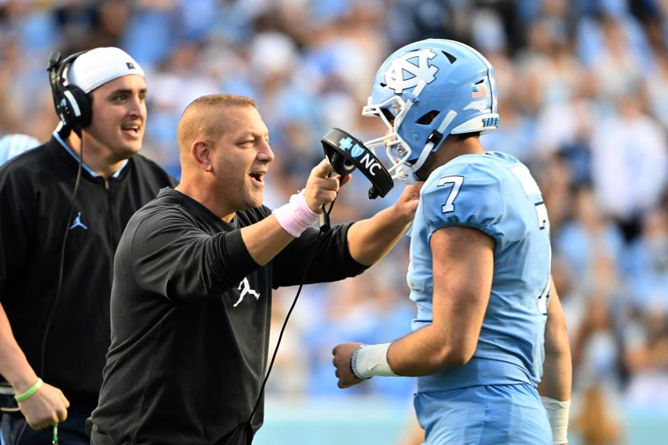 North Carolina quarterback Sam Howell meets with offensive coordinator Phil Longo after Howell ran for a touchdown during a game in 2021.