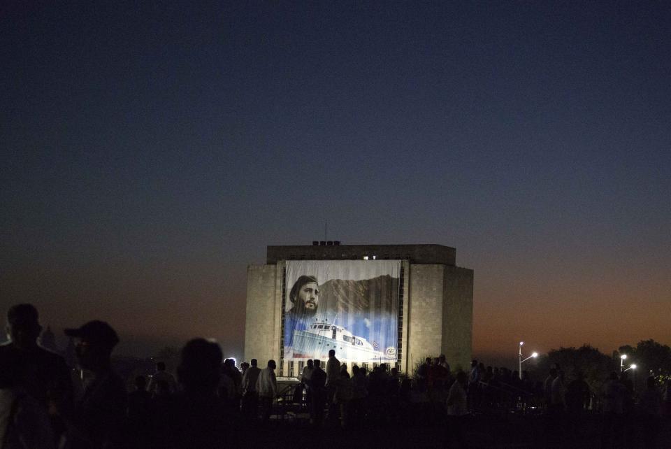 FILE - In this Jan. 2, 2017 file photo, a portrait of Fidel Castro with the Granma yacht hangs from the National Library at dawn before a parade in Castro's honor at Revolution Square in Havana, Cuba. The boat was used by Castro in 1956 to sail to Cuba from Mexico at the start of his rebel movement. (AP Photo/Desmond Boylan, File)