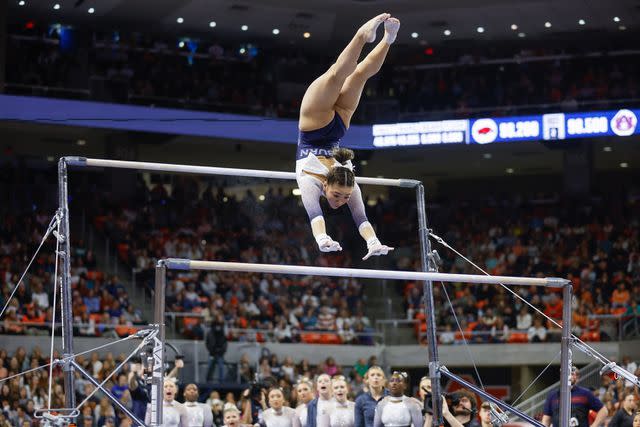 <p>Stew Milne/Getty </p> Suni Lee competes on the uneven bars for Auburn University on Jan. 20.