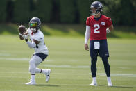 Seattle Seahawks free safety Ugo Amadi, left, catches the football as quarterback Drew Lock (2) looks on before NFL football practice Monday, Aug. 1, 2022, in Renton, Wash. (AP Photo/Ted S. Warren)