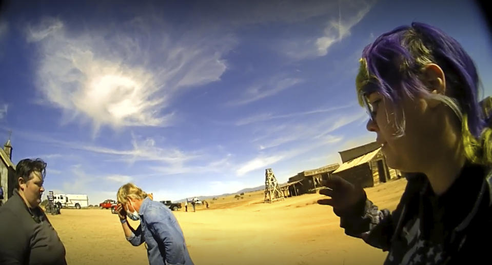 In this screen grab from lapel camera video provided by the Santa Fe County Sheriff's Office, movie set armorer Hannah Gutierrez-Reed, right, speaks with a sheriff's deputy as other colleagues, at center and left, react on the set of the western move "Rust," shortly after the fatal shooting of cinematographer Halyna Hutchins by Alec Baldwin during a rehearsal, Oct. 21, 2021, in New Mexico. The scheduled trial next week of the movie weapons supervisor in the fatal shooting of a cinematographer by Alec Baldwin may hinge on an enduring mystery: How did live ammunition find its way onto the set of a film set where it was expressly prohibited? (Santa Fe County Sheriff's Office via AP)