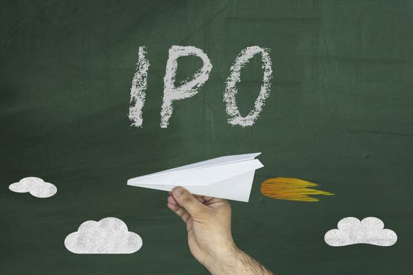 IPO written on chalkboard with hand holding paper airplane below it