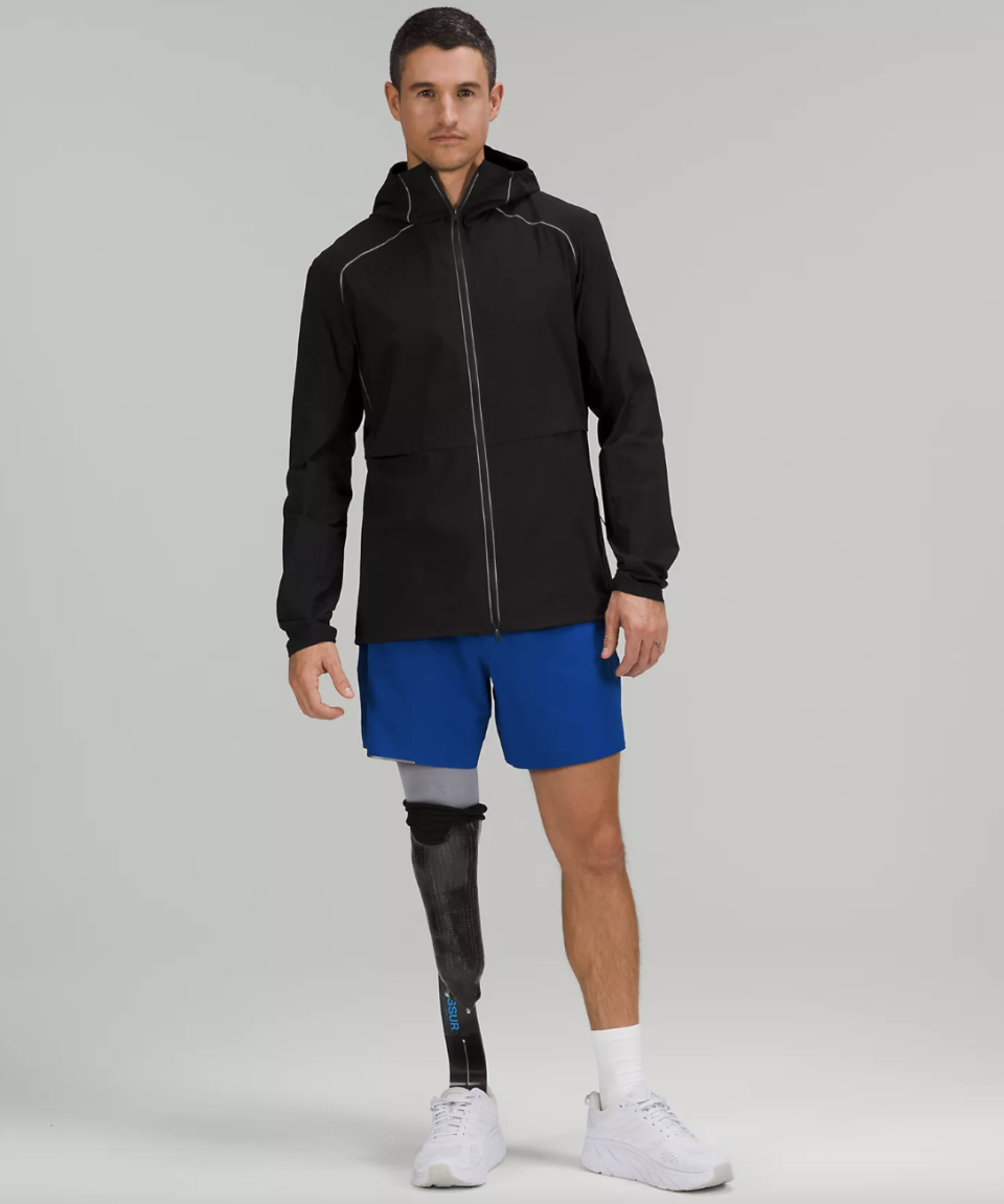man in blue shorts and prosthetic leg wearing white sneakers and black Fast and Free Windbreaker (Photo via lululemon)