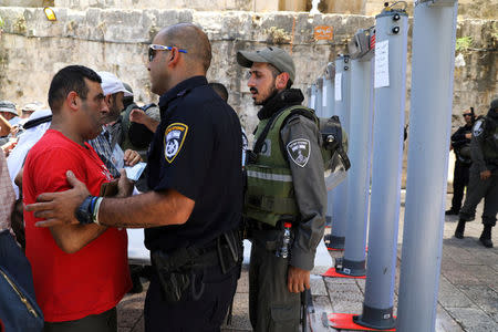 An Israeli police officer checks the identity of a Palestinian man next to newly installed metal detectors at an entrance to the compound known to Muslims as Noble Sanctuary and to Jews as Temple Mount, in Jerusalem's Old City July 16, 2017. REUTERS/Ammar Awad