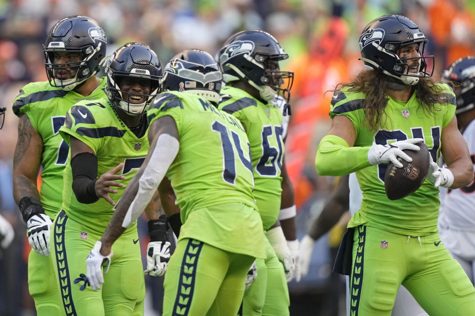 Seattle Seahawks quarterback Geno Smith, second from left, celebrates with wide receiver DK Metcalf (14) after tight end Colby Parkinson (84) caught a pass for a touchdown against the Denver Broncos during the first half of an NFL football game, Monday, Sept. 12, 2022, in Seattle. (AP Photo/Stephen Brashear)