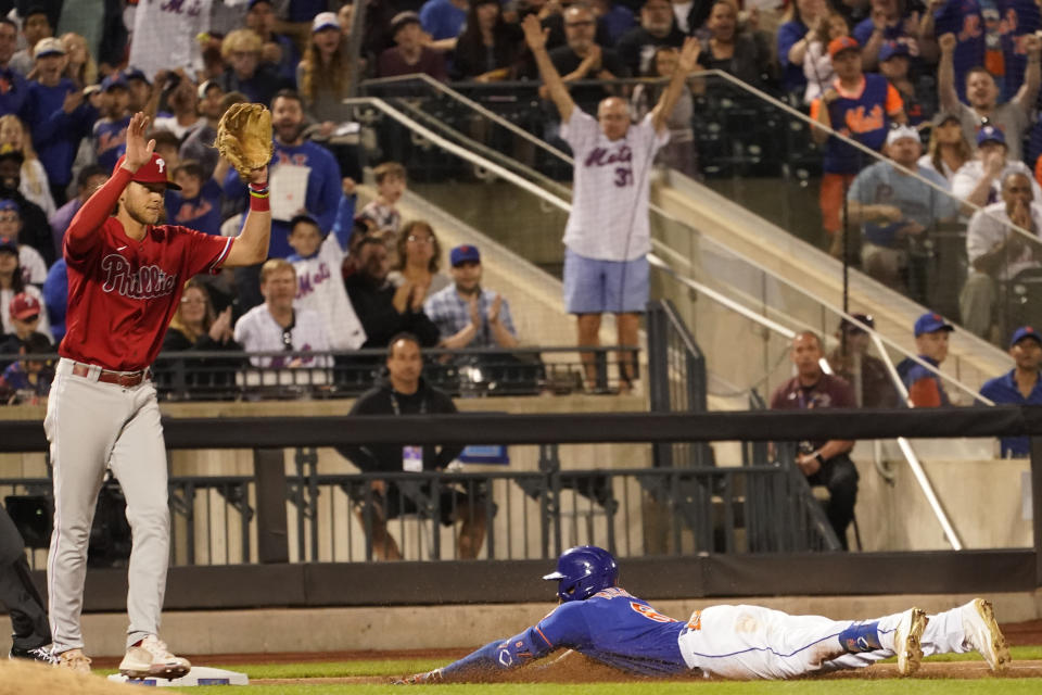 Philadelphia Phillies third baseman Alec Bohm, left, reacts as New York Mets' Starling Marte slides into third after hitting a triple during the fifth inning of a baseball game, Sunday, May 29, 2022, in New York. (AP Photo/Mary Altaffer)