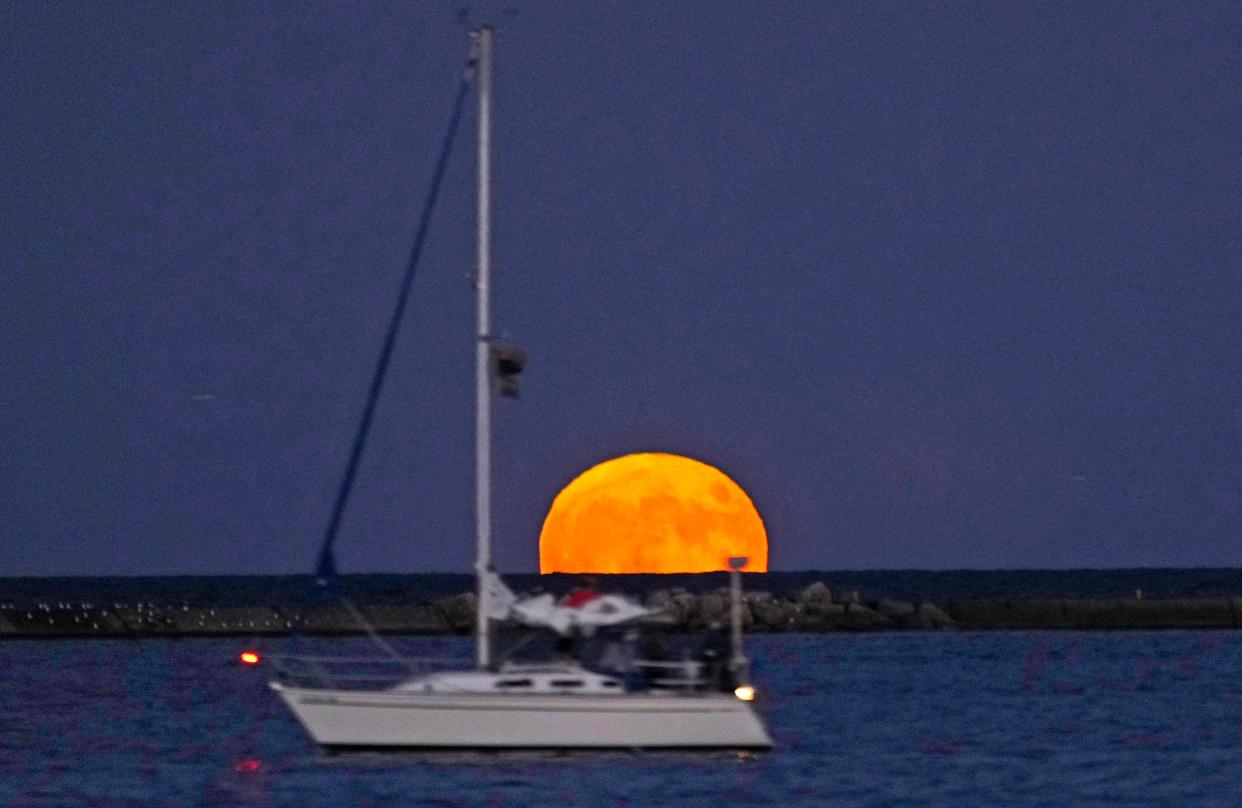 A sailboat passes by a full supermoon, called the Buck Moon, as it rises over Lake Michigan in Milwaukee on Wednesday, July 13, 2022.