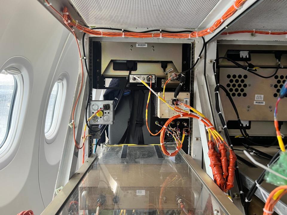 Inside the 737 MAX 10 testbed with orange wiring and black computer boxes.