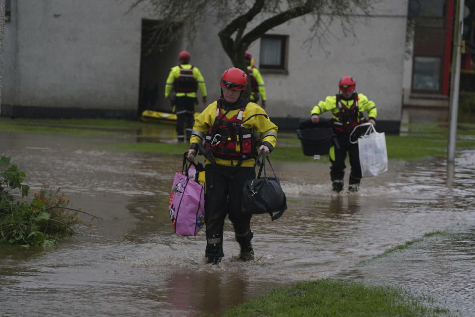 Members of the emergency services carry residents belongings to safety as Storm Babet batters the country in Brechin, Scotland, Friday Oct. 20, 2023. Flood warnings are in place in Scotland, as well as parts of northern England and the Midlands. (Andrew Milligan/PA via AP)