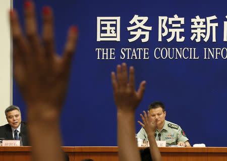 Journalists raise their hands to ask questions to Spokesperson of Chinese Ministry of National Defense Senior Colonel Yang Yujun (R) during a news conference about the annual white paper on China's military strategy in Beijing, China, May 26, 2015. REUTERS/Kim Kyung-Hoon