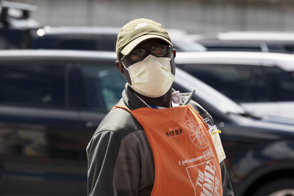 A Home Depot employee wears a protective mask while on the job, Saturday, April 11, 2020, in Somerville, Mass. The new coronavirus causes mild or moderate symptoms for most people, but for some, especially older adults and people with existing health problems,  it can cause more severe illness or death. (AP Photo/Michael Dwyer)