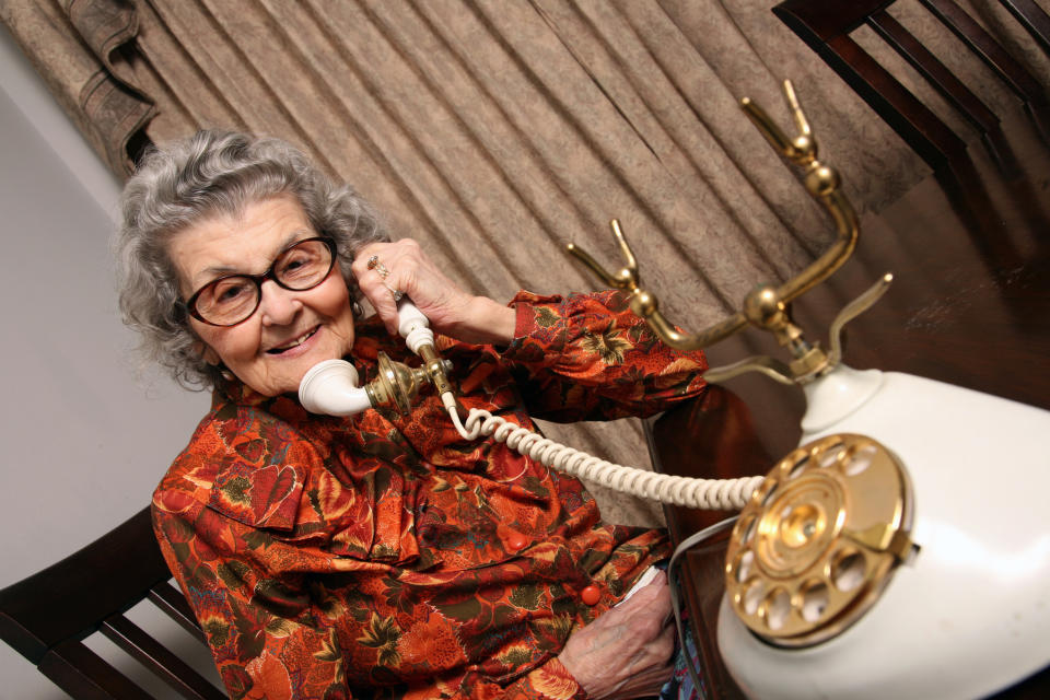 An old woman using a landline phone
