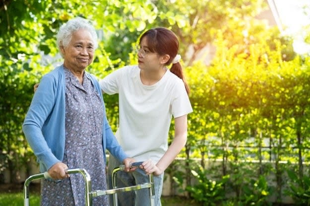 An elderly woman with a walker receiving help from a younger woman