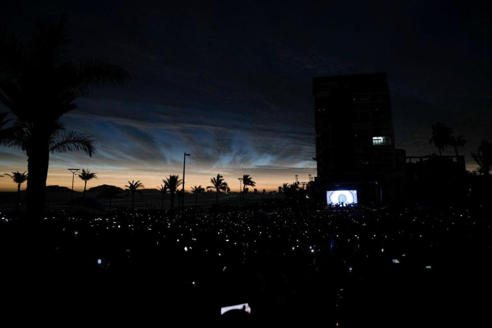 People use the light from their mobile phones as the solar eclipse darkens the sky in Mexico (AP)