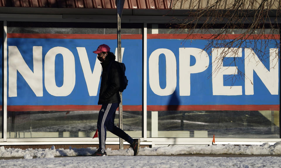 FILE - In this Feb. 25, 2021, file photo, a pedestrian in a face covering walks past the sign plastered on the windows of a restaurant to announce that it is open after closure because of the coronavirus in Boulder, Colo. While most Americans have weathered the pandemic financially, about 38 million say they are worse off now than before the outbreak began in the U.S. According to a new poll from Impact Genome and The Associated Press-NORC Center for Public Affairs Research 55% of Americans say their financial circumstances are about the same now as a year ago, and 30% say their finances have improved. (AP Photo/David Zalubowski, File)