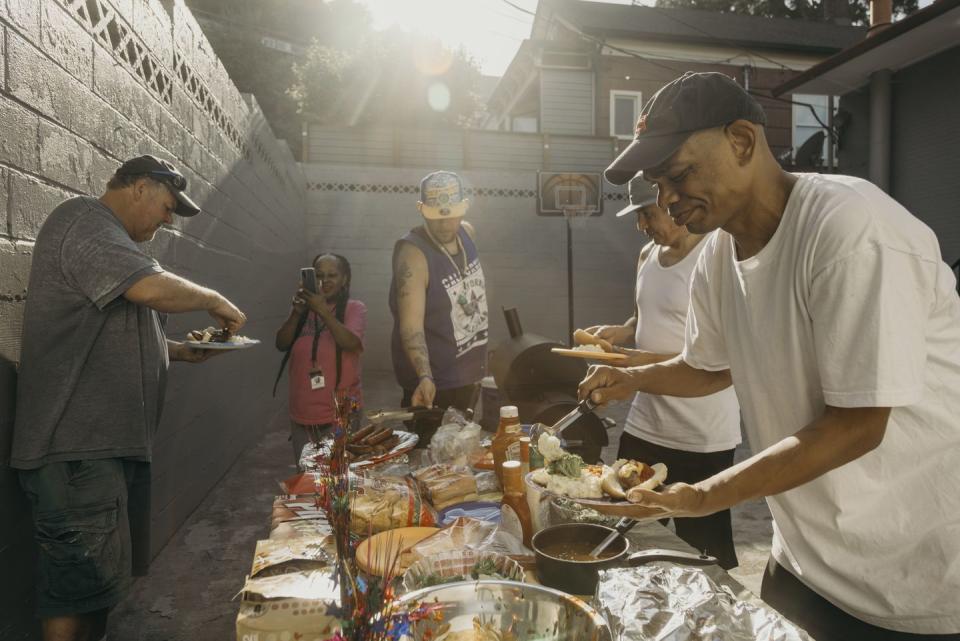 residents of the motel 6th avenue enjoy a cookout on a sunny evening