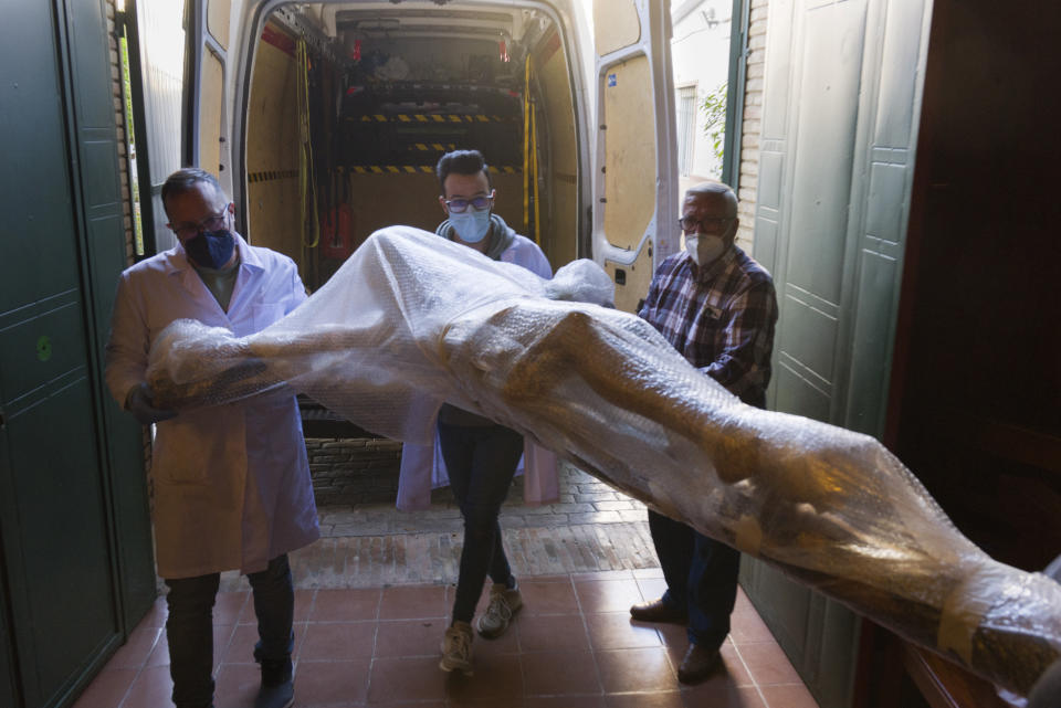 A restored figure of Jesus arrives into Nuestra Senora de la Candelaria church in Seville, southern Spain, Thursday, March 25, 2021. Few Catholics in devout southern Spain would have imagined an April without the pomp and ceremony of Holy Week processions. With the coronavirus pandemic unremitting, they will miss them for a second year. (AP Photo/Laura Leon)