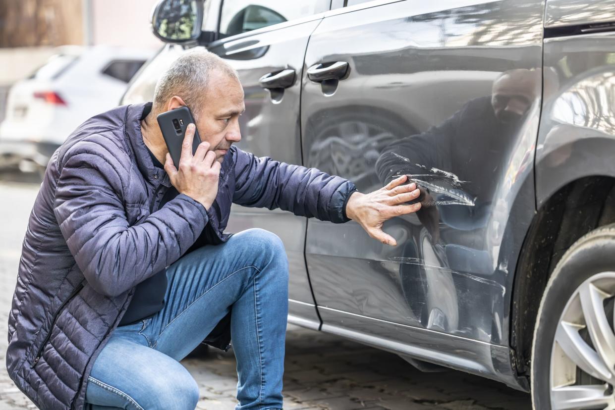 A man calls the insurance company or the police because someone backed into the side door of his car in the parking lot.