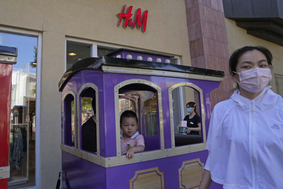 A child in a toy train passes a H&M store in Beijing on Thursday, June 3, 2021. The Chinese government has accused H&M, Nike, Zara and other brands of importing unsafe or poor quality children's clothes and other goods, adding to headaches for foreign companies after Beijing attacked them over complaints about possible forced labor in the country's northwest. (AP Photo/Ng Han Guan)