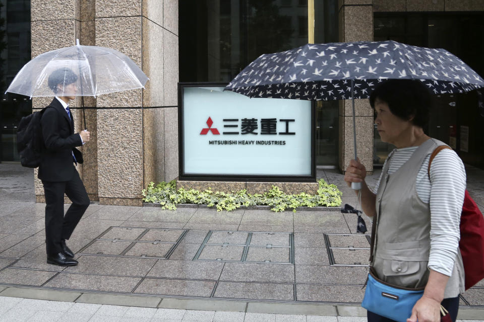 People walk past the company sign of the Mitsubishi Heavy Industries in Tokyo Tuesday, July 16, 2019. Colonial-era Korean laborers are seeking a court approval for the sales of local assets of their former Japanese company as it is refusing to compensate them. Lawyers for Koreans who worked for the Japanese company say they’ll soon request a South Korean court to authorize the sales of some of Mitsubishi’s seized assets in South Korea. (AP Photo/Koji Sasahara)