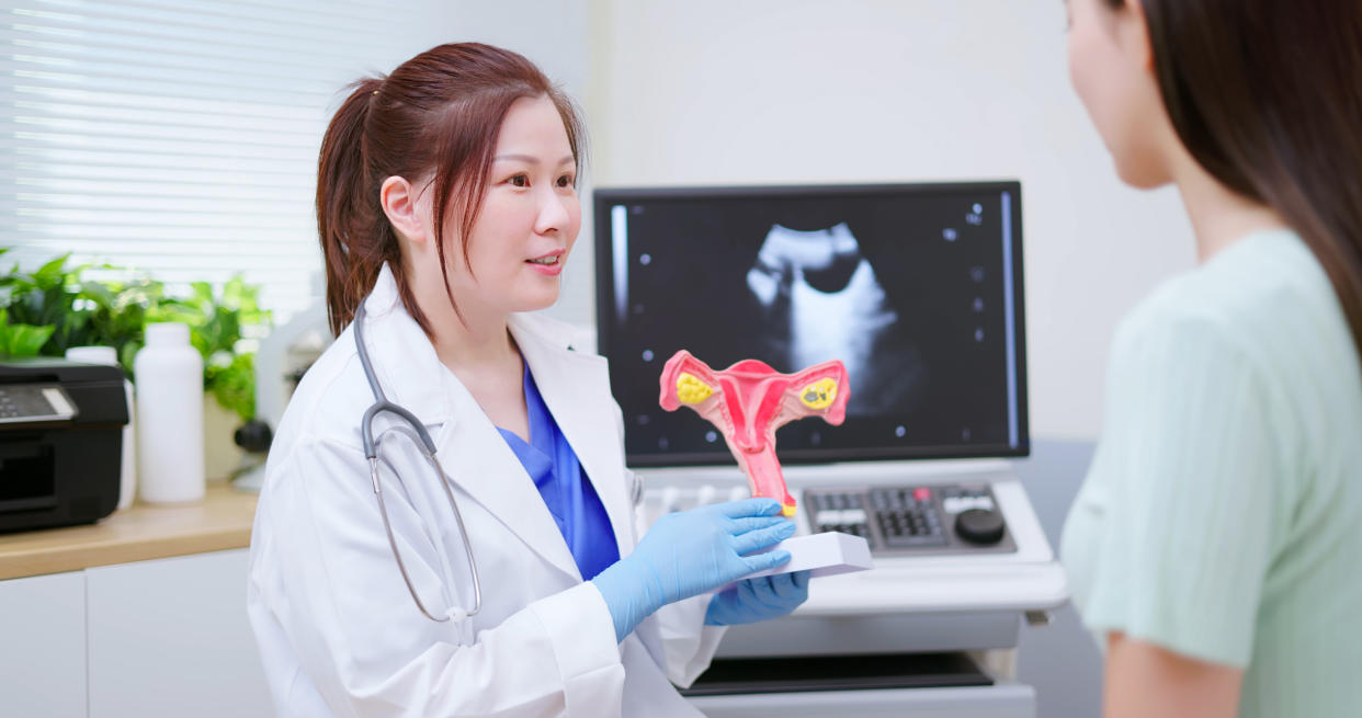 doctor explaining uterus model to woman in hospital