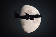 <p>A passenger aircraft flies in front of the moon over central London. (PA Images) </p>