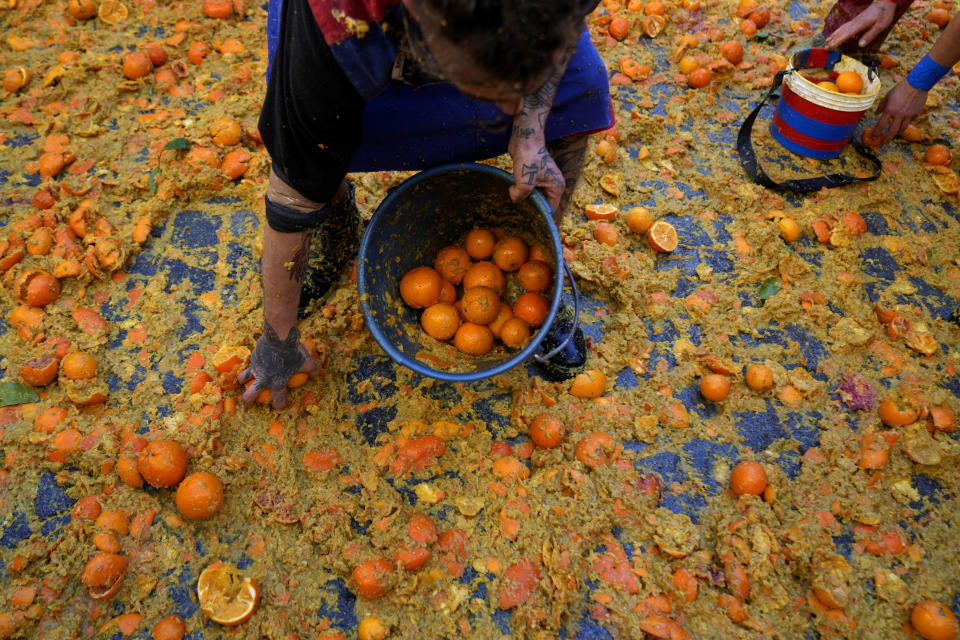 A man holds a bucket of oranges during the 'Battle of the Oranges" where people pelt each other with oranges as part of Carnival celebrations in the northern Italian Piedmont town of Ivrea, Italy, Tuesday, Feb. 13, 2024. (AP Photo/Antonio Calanni)