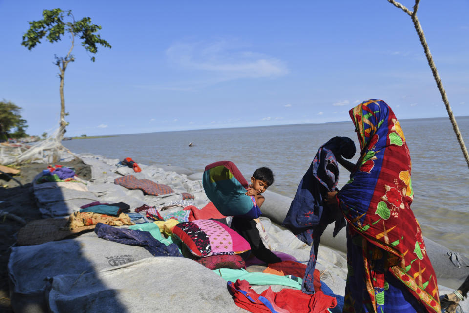 A Bangladeshi woman and a child try to salvage their belongings after tropical storm Sitrang lashed the Bay of Bengal coast in Char Fasson, Bhola district, Bangladesh, Tuesday, Oct.25, 2022. (AP Photo/ Zabed Hasnain Chowdhury)