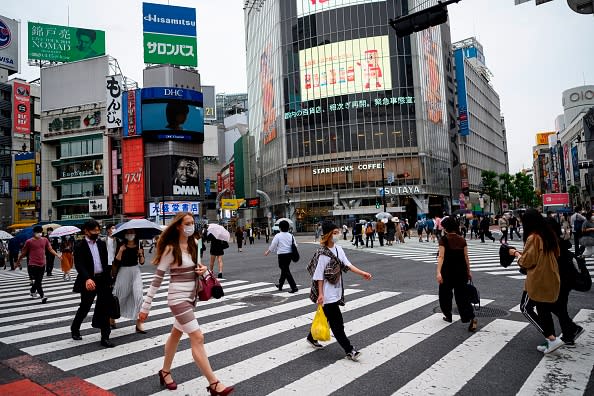 People wearing face masks amid concerns over the spread of the COVID-19 coronavirus walk across the Shibuya Crossing in Tokyo.