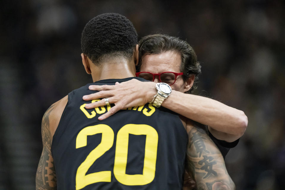 Utah Jazz forward John Collins (20) and Atlanta Hawks head coach Quin Snyder, right, embrace on the court during the first half of an NBA basketball game, Friday, March 15, 2024, in Salt Lake City. Friday night's game was Snyder's first time coaching back in Salt Lake City since departing as head coach of the Jazz. (AP Photo/Spenser Heaps)