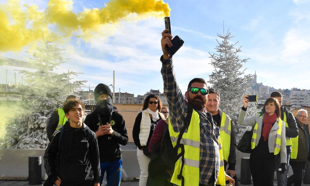 The gilets jaunes hold up a smoke grenade in a demonstration in Marseilles last week