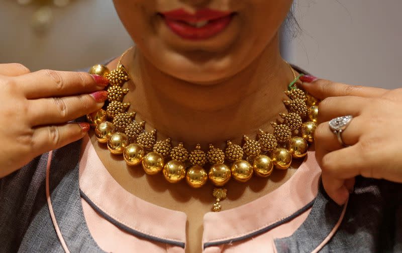 FILE PHOTO: A saleswoman displays a gold necklace to a customer inside a jewellery showroom on the occasion of Akshaya Tritiya, a major gold buying festival, in Mumbai