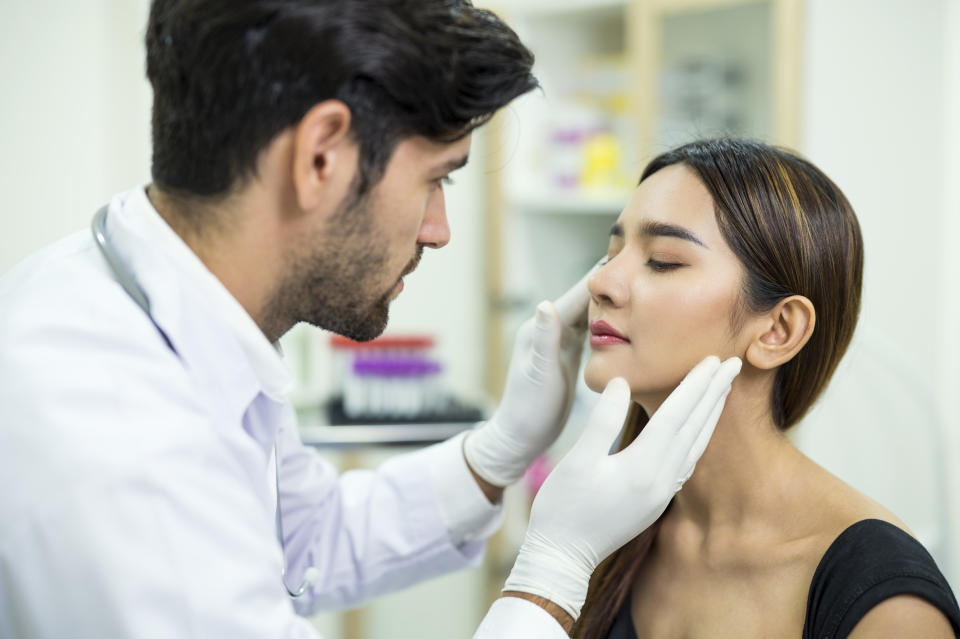 Doctor examining and explaining Asian women patient's face for improvement of her skin at a beauty clinic. Skin care clinic business.