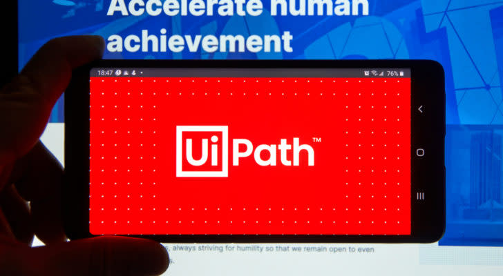The UiPath logo on a smartphone in front of a computer screen.