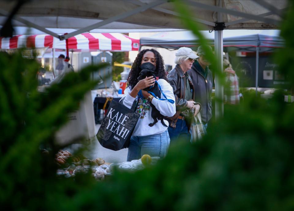 Mathany Ahmed of Des Moines holds her dog, Remi, as she buys strawberries from the StoryBook Orchard stand during the opening day of the 2022 Downtown Des Moines Farmers' Market.