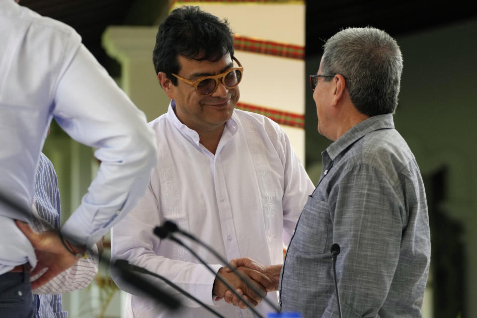 Ivan Danilo Rueda, High Commissioner for Peace on behalf of the Colombian government, center, shakes hands with Pablo Beltran of the Colombian guerrilla National Liberation Army (ELN) after a signing ceremony to resume peace talks, at the Casa Cultural Aquiles Nazoa in Caracas, Venezuela, Tuesday, Oct. 4, 2022. The agreement comes after more than four years of suspension, and will start in November. (AP Photo/Ariana Cubillos)