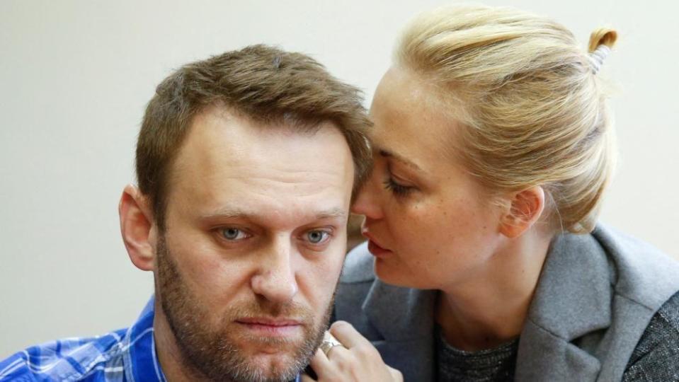 Alexei Navalny is seen with his wife Yulia appearing to whisper into his ear