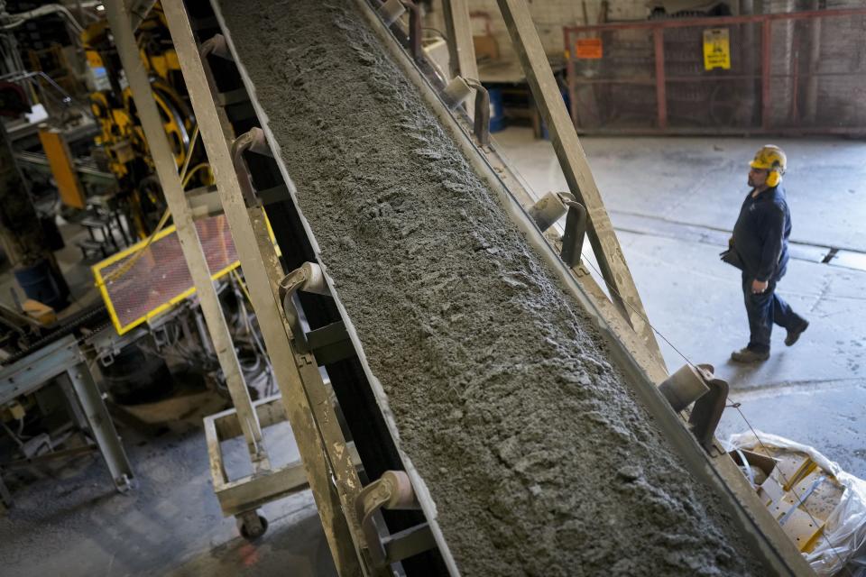 Fresh concrete is fed via a conveyor belt into a forming machine, producing blocks designed with liquid carbon dioxide as an ingredient at the Glenwood Mason Supply Company, Tuesday, April 18, 2023, in the Brooklyn borough of New York. New York is forcing buildings to clean up, and several are experimenting with capturing the carbon dioxide, cooling it into a liquid and mixing it into concrete where it turns into a mineral. (AP Photo/John Minchillo)
