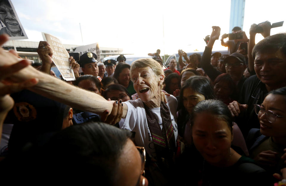 Australian Roman Catholic nun Sister Patricia Fox reaches out to bid goodbye to supporters as she is escorted to the Ninoy Aquino International Airport for her flight to Australia Saturday, Nov. 3, 2018, in Manila, Philippines. Sister Fox decided to leave after 27 years in the country after the Immigration Bureau denied her application for the extension of her visa. Sr. Fox called on Filipinos to unite and fight human rights abuses ahead of her forced departure from the country. (AP Photo/Bullit Marquez)