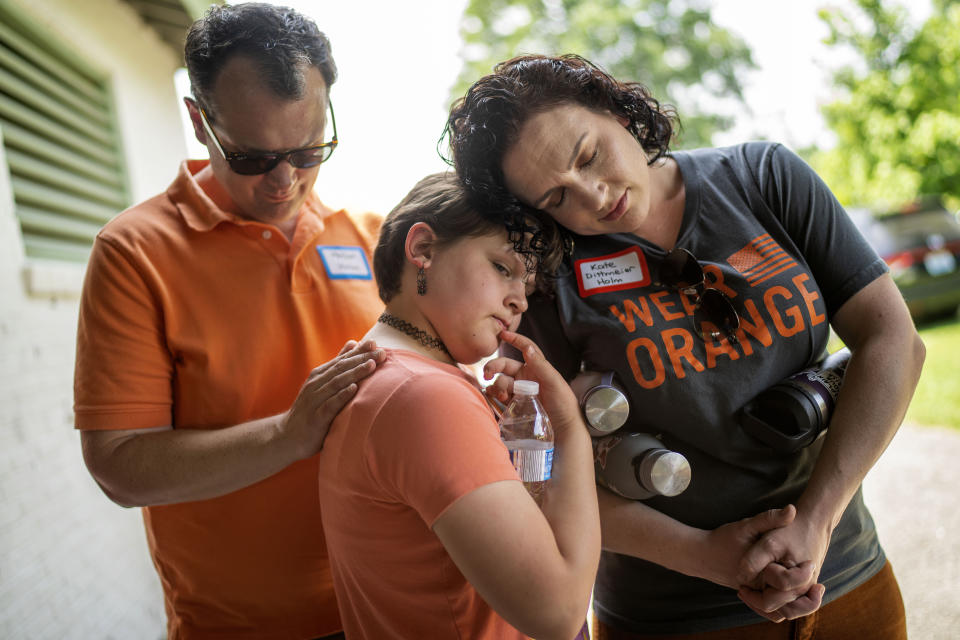 Hollan Holm, izquierda, y su esposa Kate Dittmeier Holm, derecha, guardan un minuto de silencio junto con su hija Sylvia, de 11 años, durante un mitin en contra de la violencia con armas el sábado 3 de junio de 2023, en Louisville, Kentucky. (AP Foto/David Goldman)