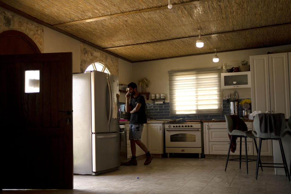 Israeli settler Yinon Levi speaks on his phone in the kitchen at his farm in the West Bank settlement outpost of Meitarim, Sunday, May 12, 2024. Levi was sanctioned by the United States; he said he had trouble paying bills for weeks but then could access money again. (AP Photo/Maya Alleruzzo)