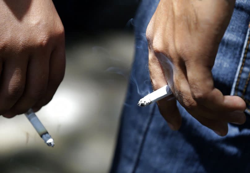 Job applicants smoke while waiting for their documents to be processed in Manila, March 2013