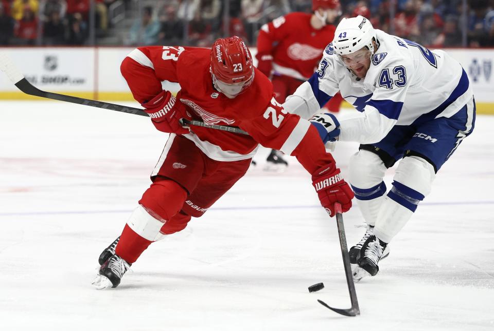 Detroit Red Wings left wing Lucas Raymond (23) battles for the puck with Tampa Bay Lightning defenseman Darren Raddysh (43) during the first period of an NHL hockey game Sunday, Jan. 21, 2024, in Detroit. (AP Photo/Duane Burleson)