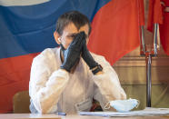 A member of the election commission wearing a face mask to protect against coronavirus infection waits for voters at a polling station in St. Petersburg, Russia, Wednesday, July 1, 2020. The vote on the constitutional amendments that would reset the clock on Russian President Vladimir Putin's tenure and enable him to serve two more six-year terms is set to wrap up Wednesday. (AP Photo/Dmitri Lovetsky)