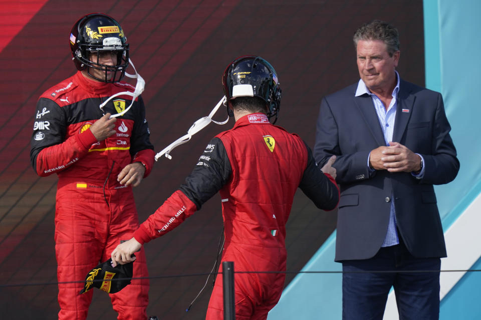 Ferrari driver Charles Leclerc, center, of Monaco and Ferrari driver Carlos Sainz of Spain wear football helmets as they speak to former Miami Dolphins quarterback Dan Marino at the Formula One Miami Grand Prix auto race at the Miami International Autodrome, Sunday, May 8, 2022, in Miami Gardens, Fla. (AP Photo/Lynne Sladky)