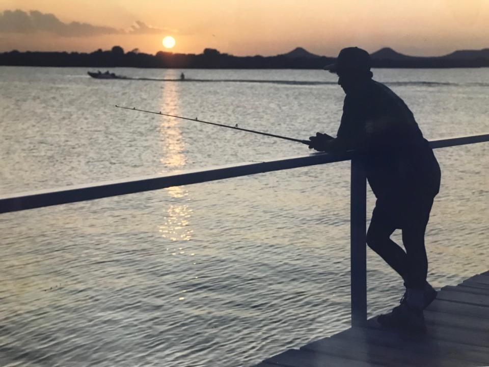 Israel Pena leans on the rail at the pier on Lake Nasworthy while fishing at sundown in August of 1992.