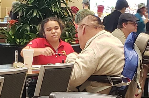 Eine Mitarbeiterin bei Chick-fil-A bekommt auf Facebook viel Aufmerksamkeit, weil sie einem Mann im Rollstuhl beim Essen hilft. (Foto: privat / Jessica Gonzalez Gomez / Facebook)