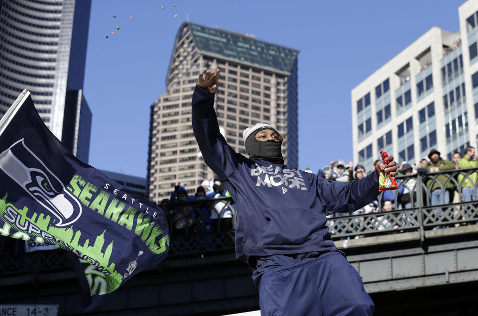 Seattle Seahawks' running back Marshawn Lynch throws pieces of candy while riding on the hood of a vehicle during the Super Bowl champions parade on Wednesday, Feb. 5, 2014, in Seattle. The Seahawks defeated the Denver Broncos 43-8 in NFL football's Super Bowl XLVIII on Sunday. (AP Photo/Elaine Thompson)