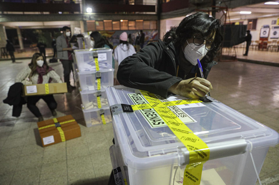 A poll worker validates a ballot box at the end of the first day the Constitutional Convention election to select assembly members that will draft a new constitution, in Santiago, Chile, Saturday, May 15, 2021. The face of a new Chile begins taking shape this weekend as the South American country elects 155 people to draft a constitution to replace one that has governed it since being imposed during a military dictatorship. (AP Photo/Esteban Felix)